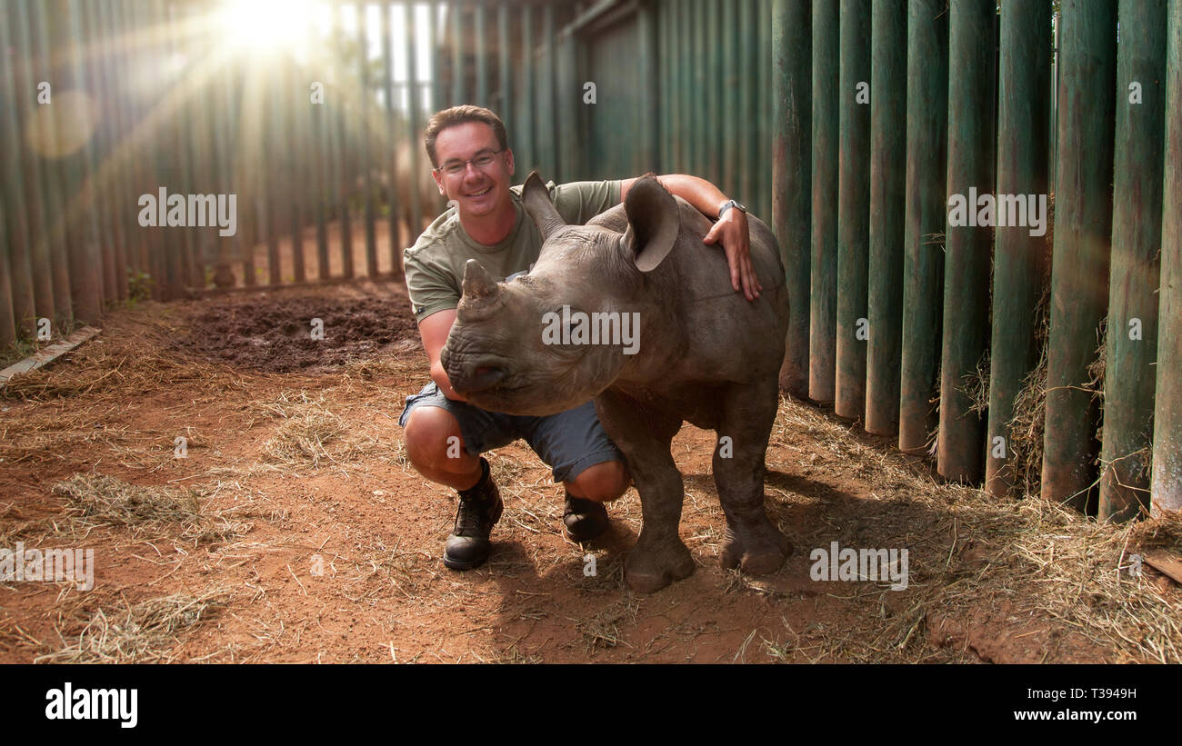 Young man with baby rhinoceros in South Africa Stock Photo
