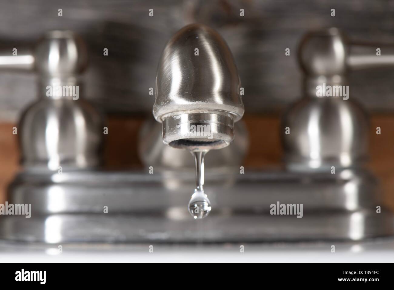Water droplet escaping from a dripping bathroom water faucet Stock