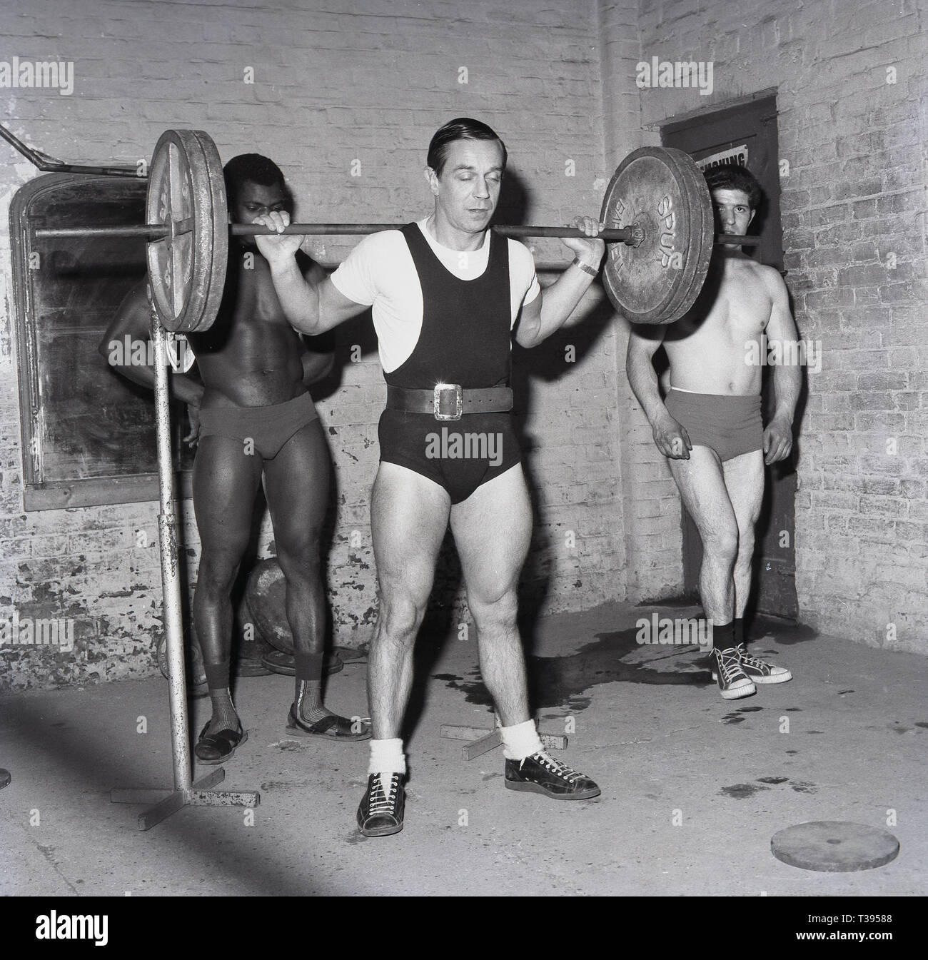 1967, historical, body buidling, man lifting weights inside an old