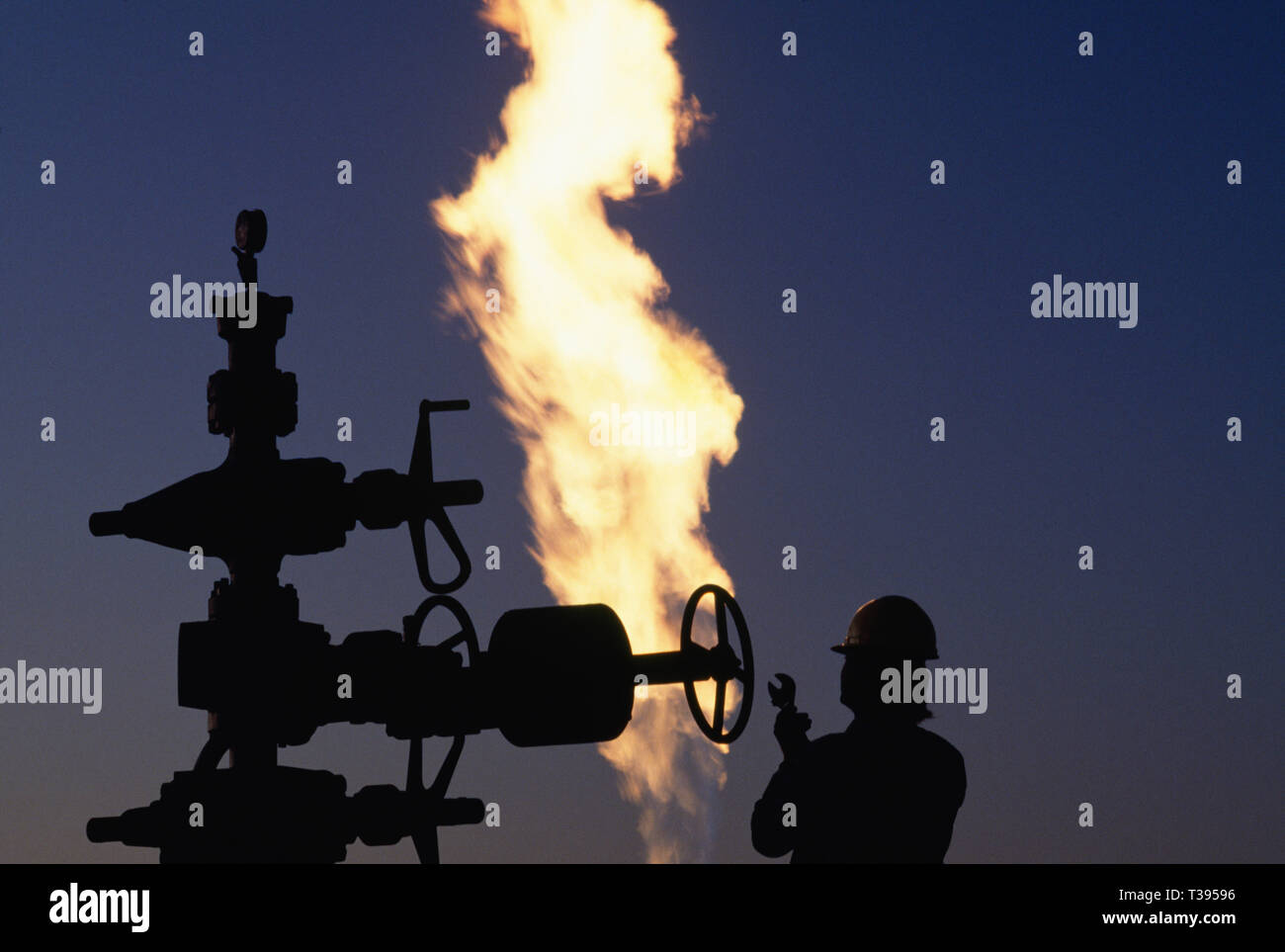 Worker adjusts valve at an Oklahoma oil field site, USA Stock Photo