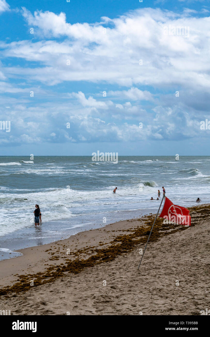 Lake Worth Florida on a high surf day. Red flags and no swimming flags are out. People are still in the water. Stock Photo