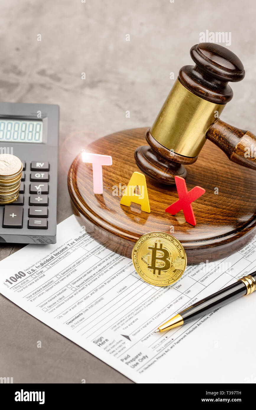 Front view of Bitcoin cryptocurrency in ront of gavel with TAX word and