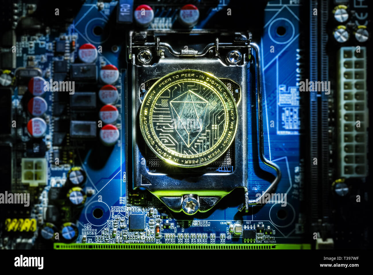 Top view of golden Eos cryptocurrency physical coin on computer mother board processor.Bitcoin mining farm, working computer equipment concept. Stock Photo
