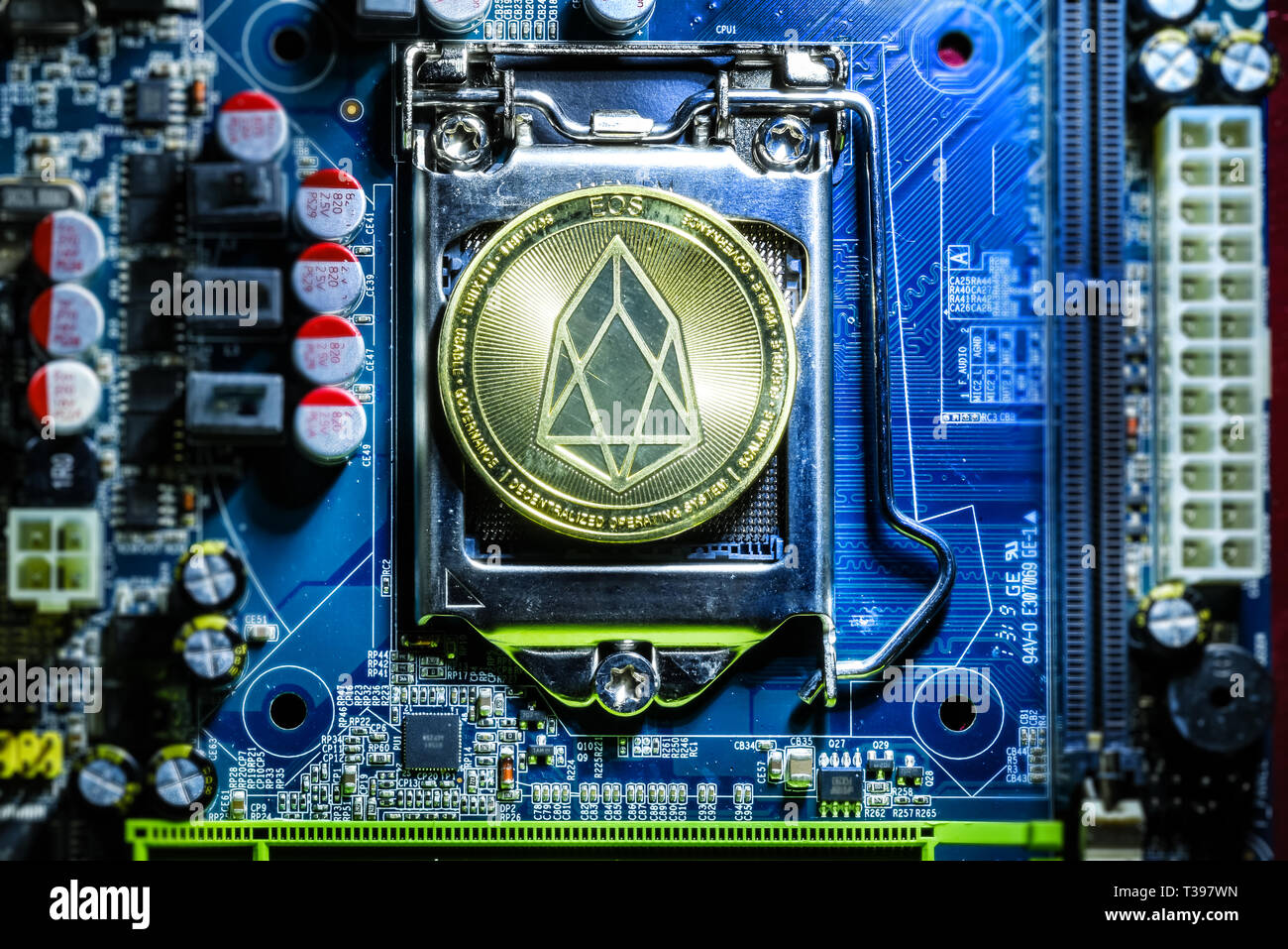 Top view of golden Eos cryptocurrency physical coin on computer mother board processor.Bitcoin mining farm, working computer equipment concept. Stock Photo