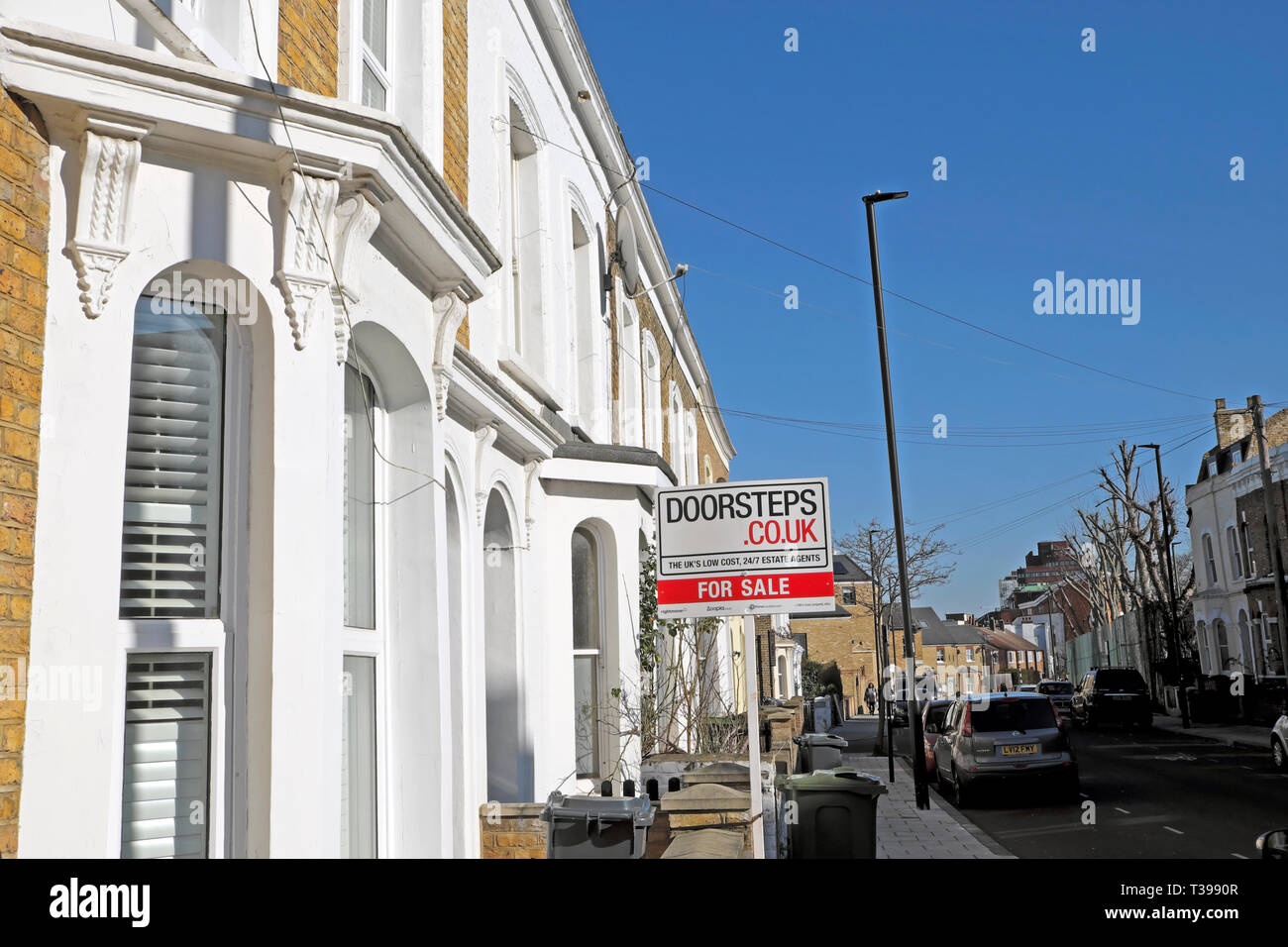 House for sale sign outside a home in a row of terraced houses on