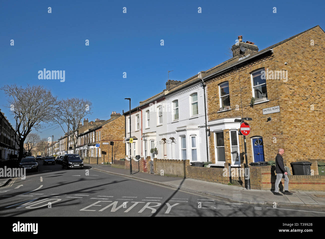 View of man walking and row of terraced housing on the corner of Dalyell Road and Pulross Rd in Brixton, South London England UK  KATHY DEWITT Stock Photo