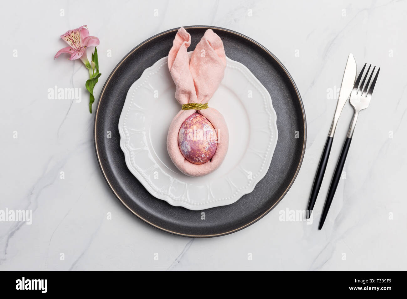 Rabbit easter egg in napkin on plate. Table setting for Easter meal. Stock Photo