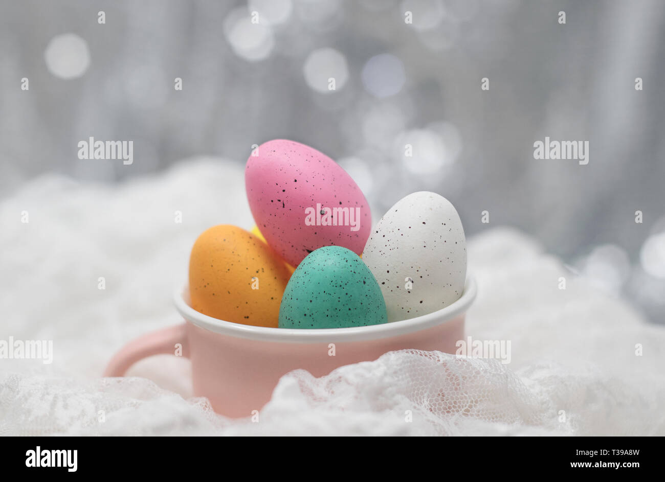 Easter eggs in a pink cup, on white lace with a soft bokeh background Stock Photo