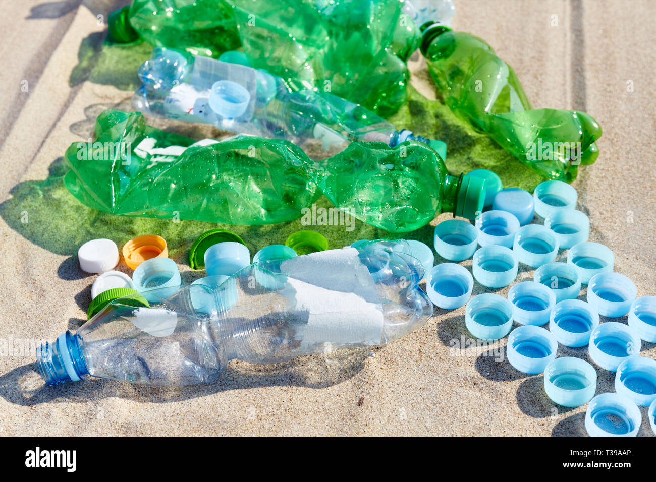 Close up picture of used plastic bottles and caps on a beach, selective focus. Stock Photo