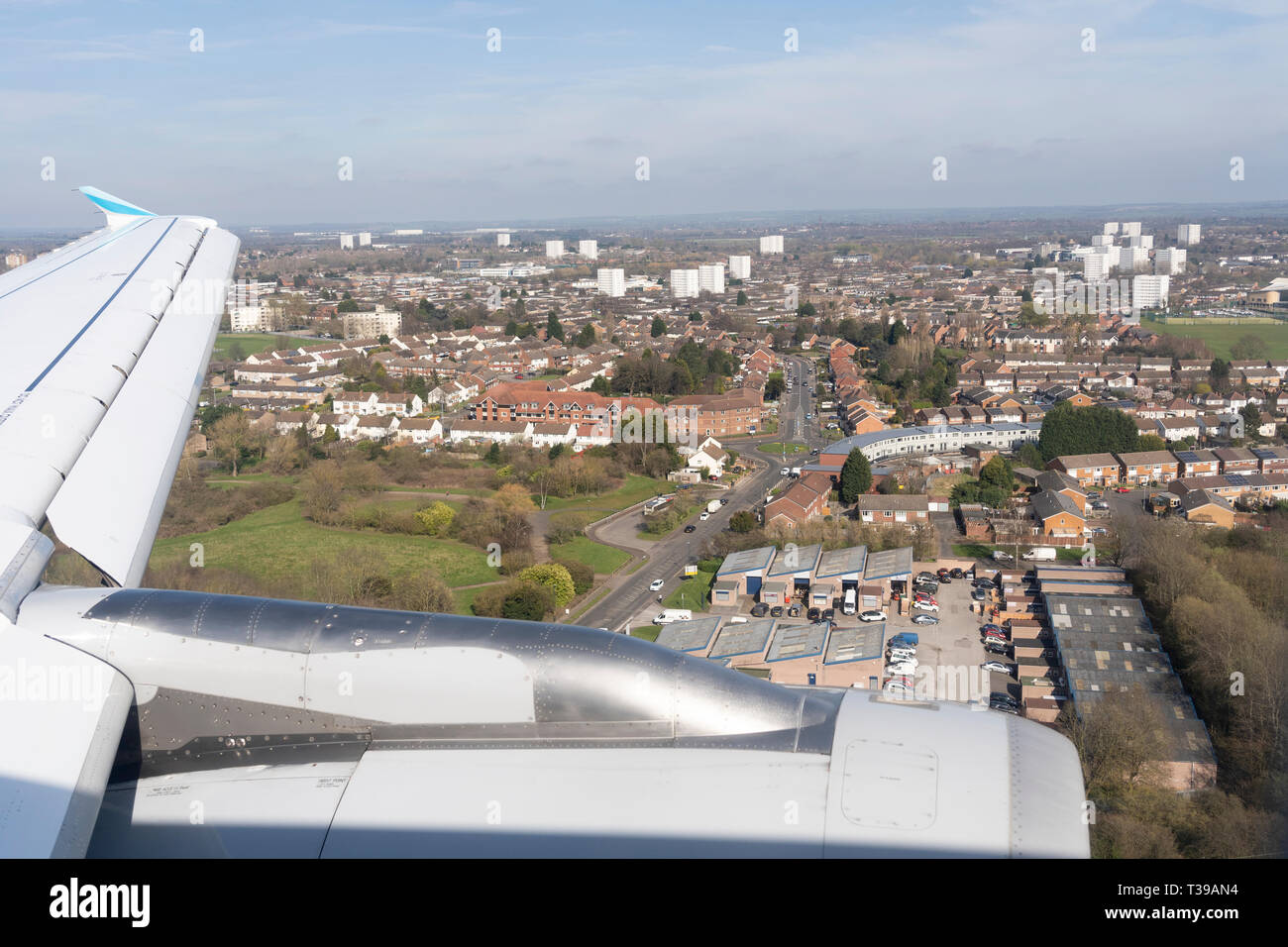 An aerial view across Birmingham and of a airliner wing and engine as a passenger jet comes in to land at Birmingham International Airport Stock Photo