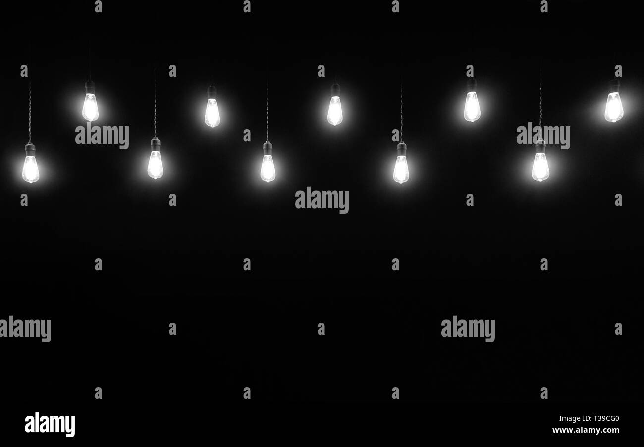 Hanging light bulbs on black background with copy space, black and white photography Stock Photo