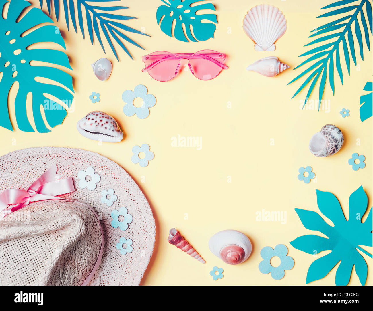 Summer background. Beach accessories with  shells and tropical leaves on light yellow background, top view. Straw hat and sunglasses. Summer holiday v Stock Photo