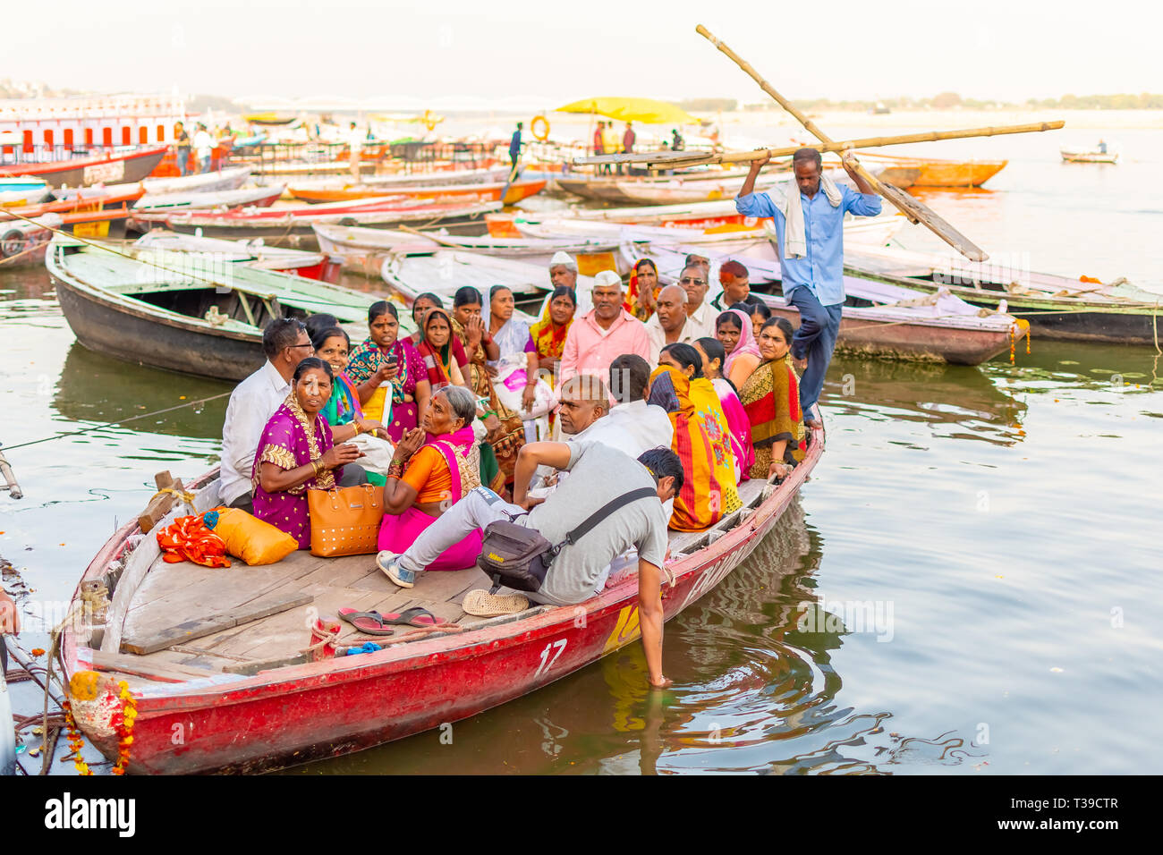 VARANASI, INDIA, 10 MAR 2019 - A lot of people sit on the crowded boats to cross the Ganges River Stock Photo
