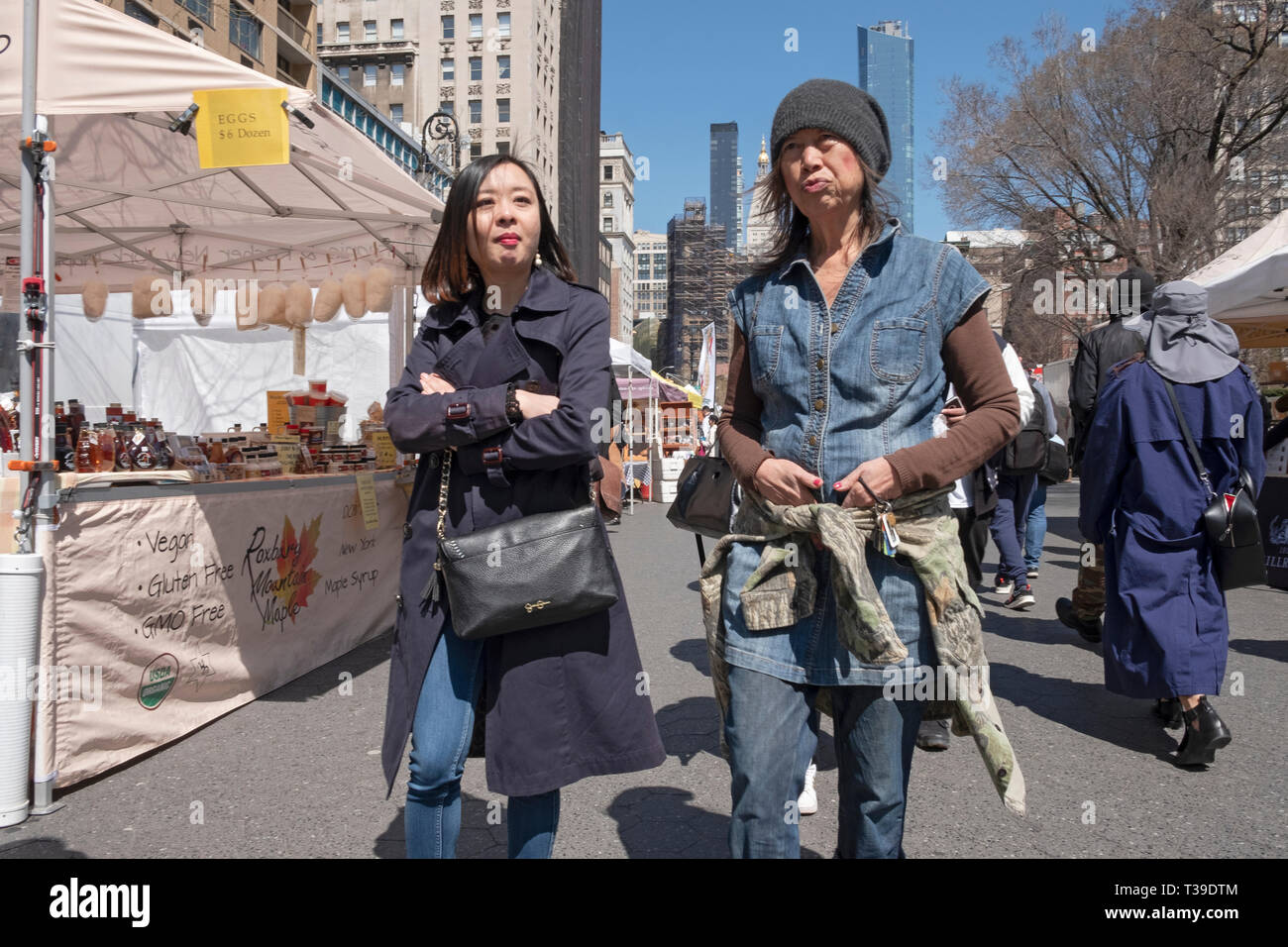 Two Asian women walk through the Union Square Green Market on a warm early Spring day. In Manhattan, New York City Stock Photo