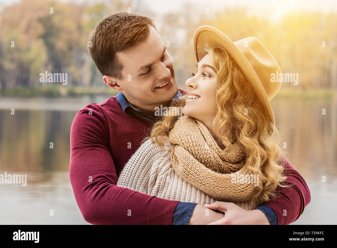 Romantic couple. Cropped image of beautiful hugging couple looking at each other and smiling while standing outdoors. Handsome man embracing his attra Stock Photo