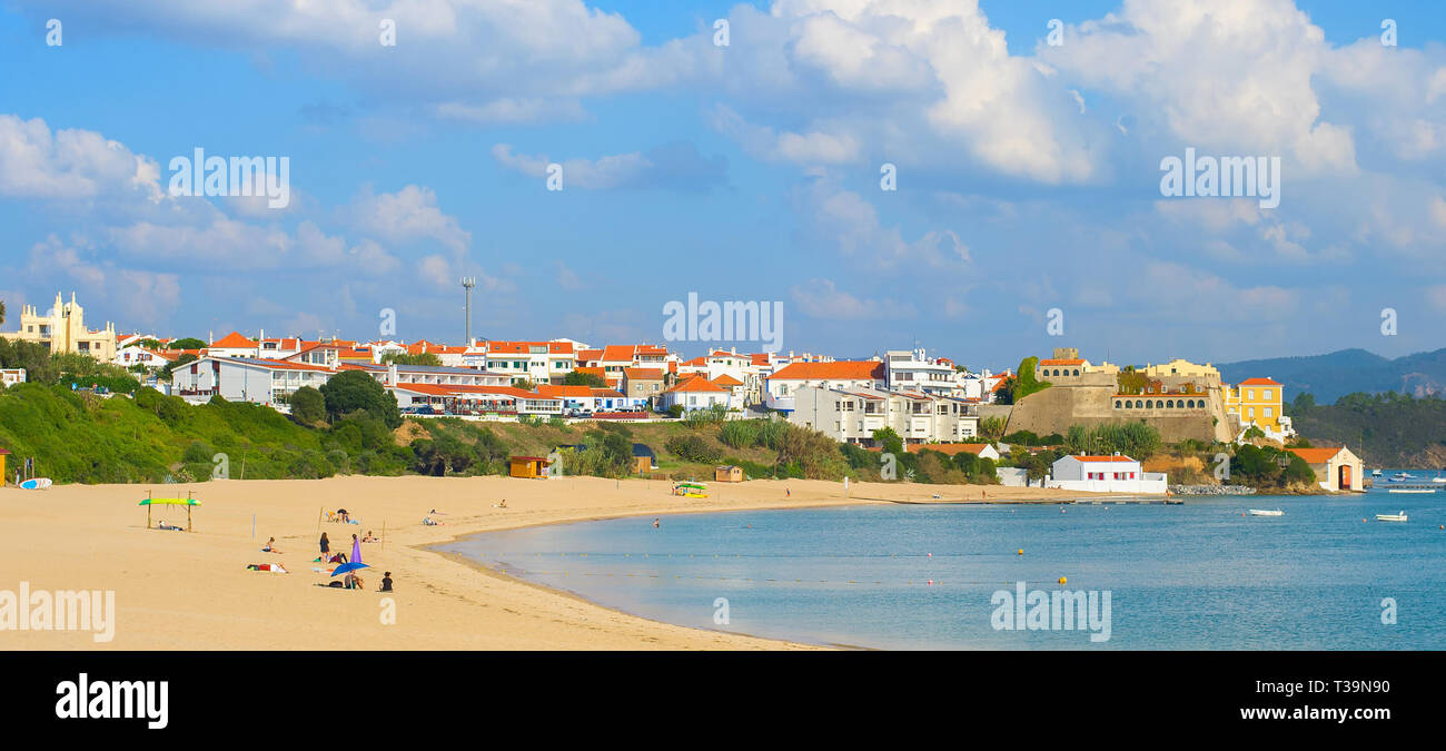 Scenic panorama of traditional village and people relaxing on river beach. Vila de Milfontes, Alentejo, Portugal Stock Photo