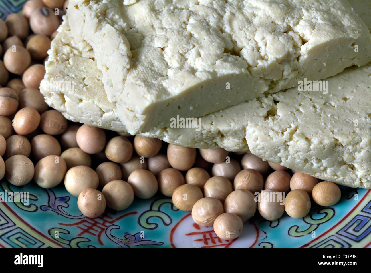 Close up of slices of tofu on uncooked soya beans. (Tofu is made from