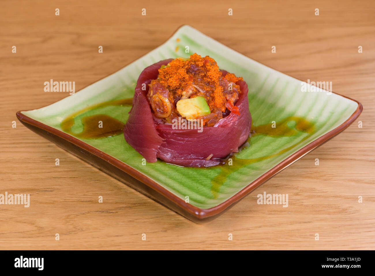 Bluefin tuna sashimi with caviar and avocado served on a square plate