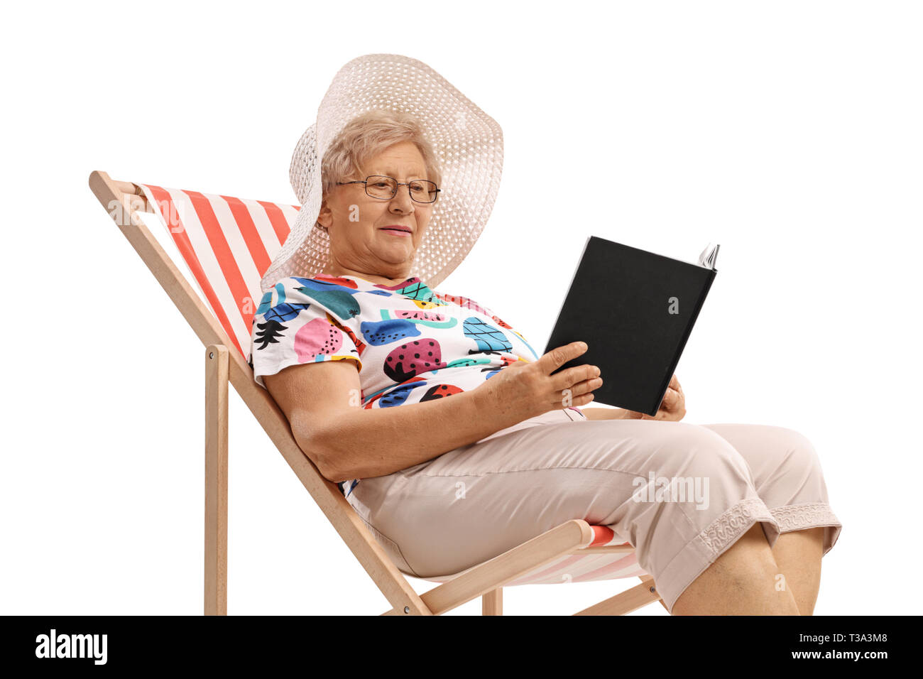 Senior woman sitting in a deck chair and reading a book isolated on ...