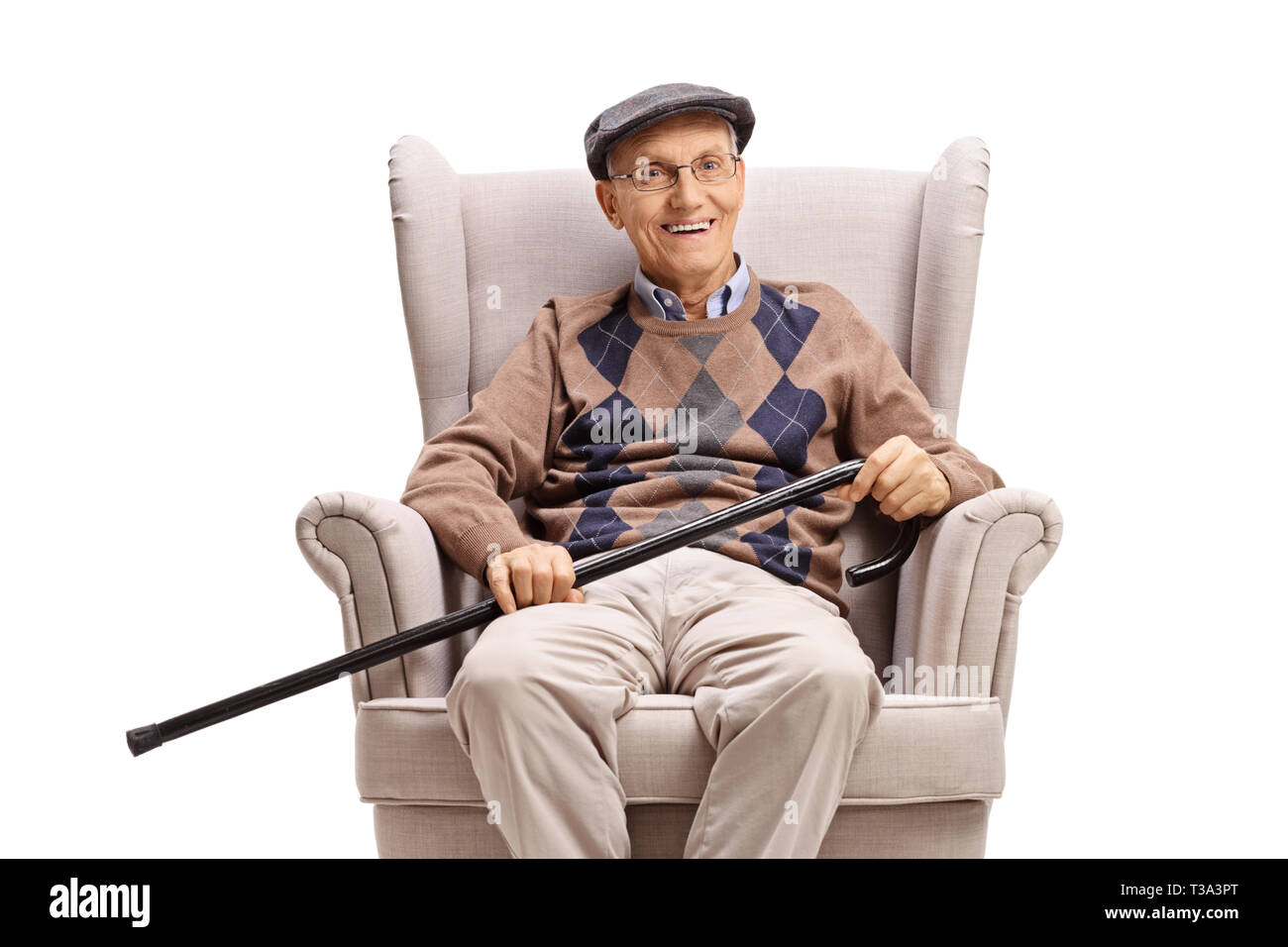 Elderly man with a walking cane sitting in an armchair and smiling at the camera isolated on white background Stock Photo