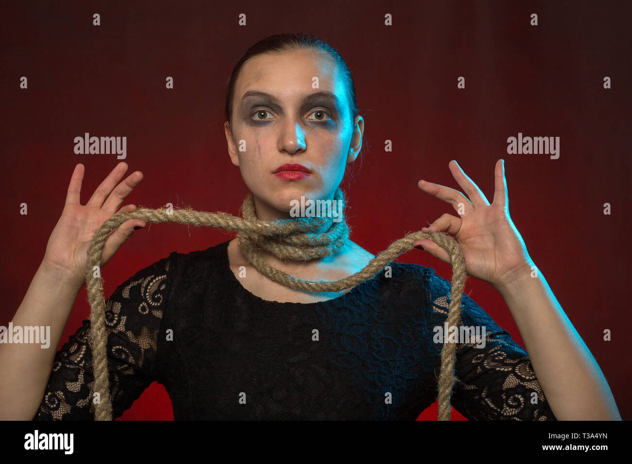 serious woman with rope on neck at red background looking at camera Stock Photo