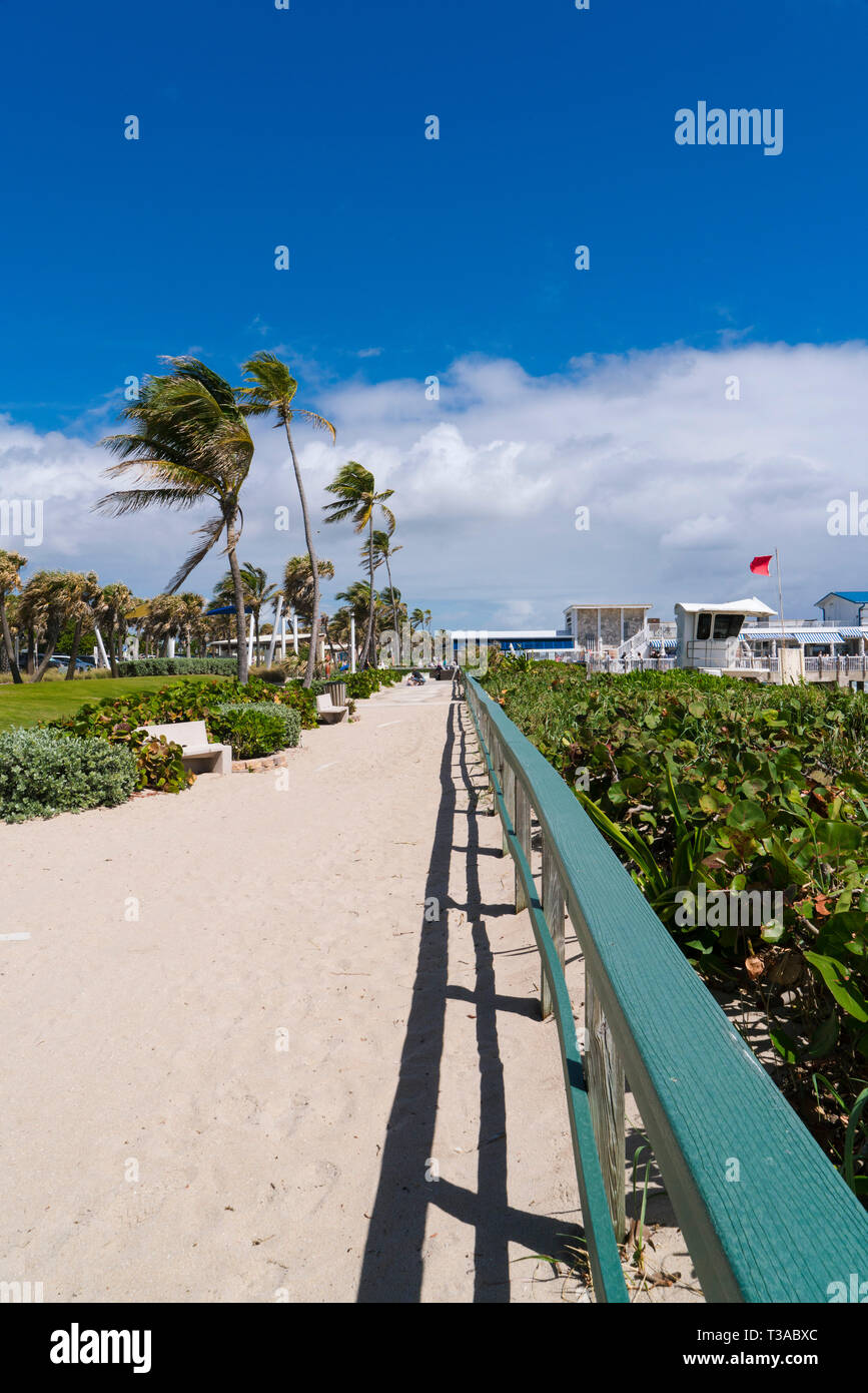Pedestrian walkway along the beach in Lake Wort Florida. The path leads to a restaurant and steps to the beach. The red flag is warning of high surf. Stock Photo