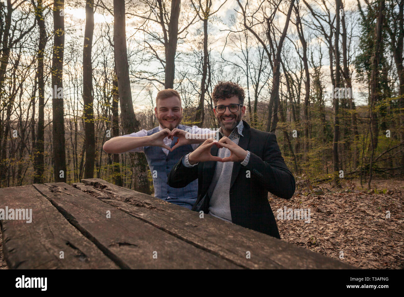 two men, gay couple, smiling and showing heart shape symbol with their hands. Stock Photo