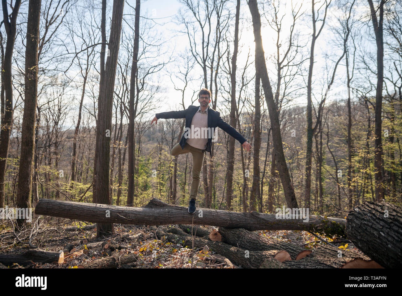 rear view, one man, dancer in smart casual clothing, doing ballet pose. outdoors in woods. Full lenght shot. Stock Photo