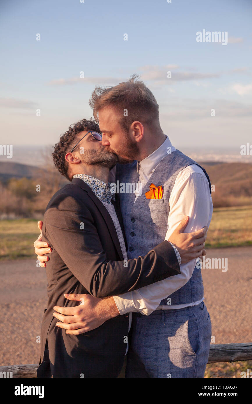 two men, gay couple hugging each other kissing, face to face. intimate and standing close by, outdoors. Stock Photo