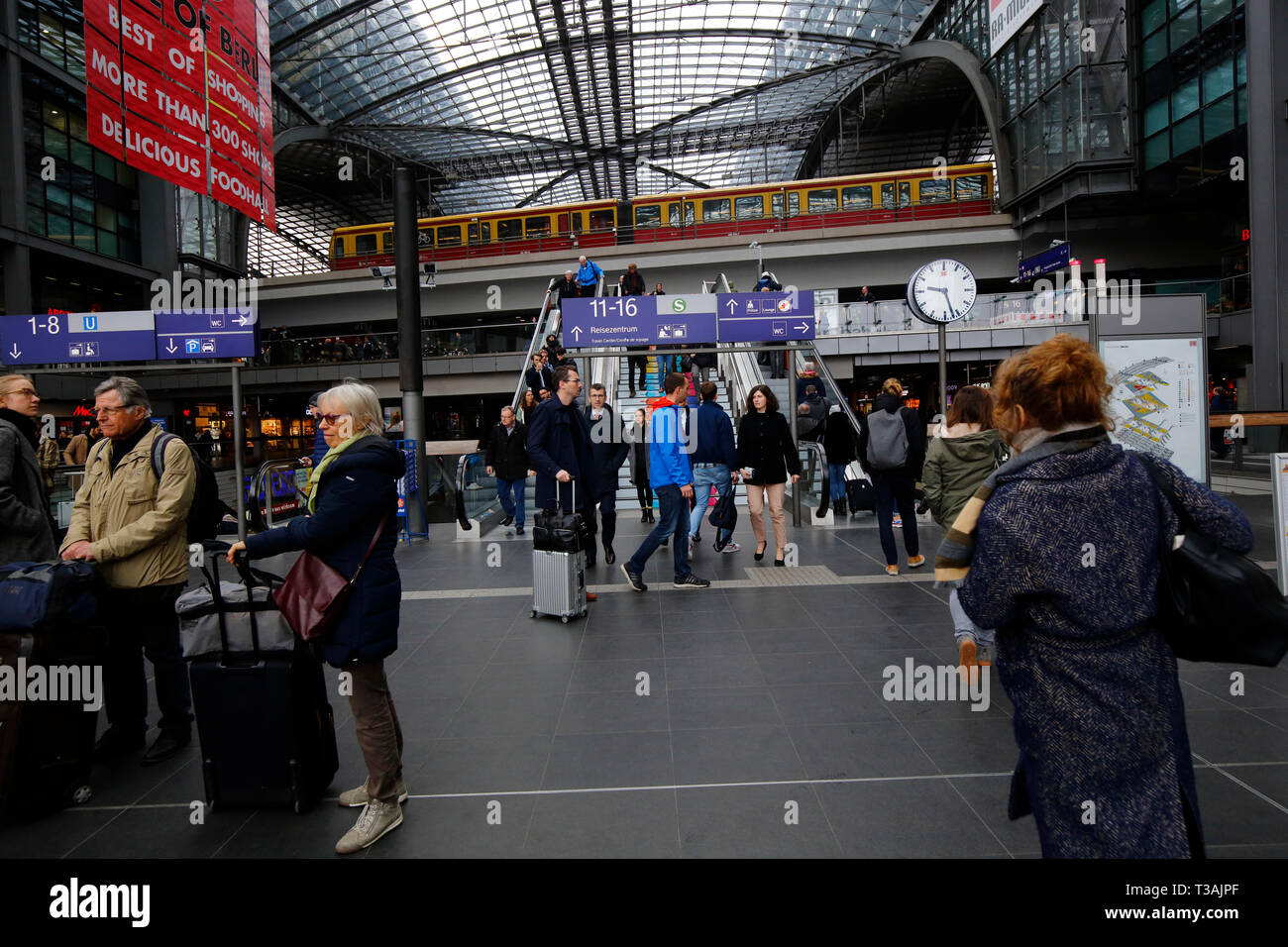 Commuters, travelers, tourists inside Berlin Hauptbahnhof shopping mall with an S Bahn train passing through overhead, Berlin, Germany Stock Photo
