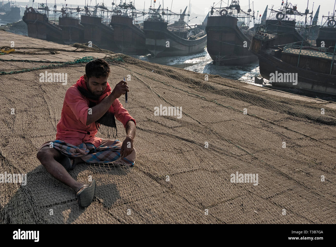 Fishermen repairing fish net at the harbor, Chittagong, Chittagong Division, Bangladesh Stock Photo