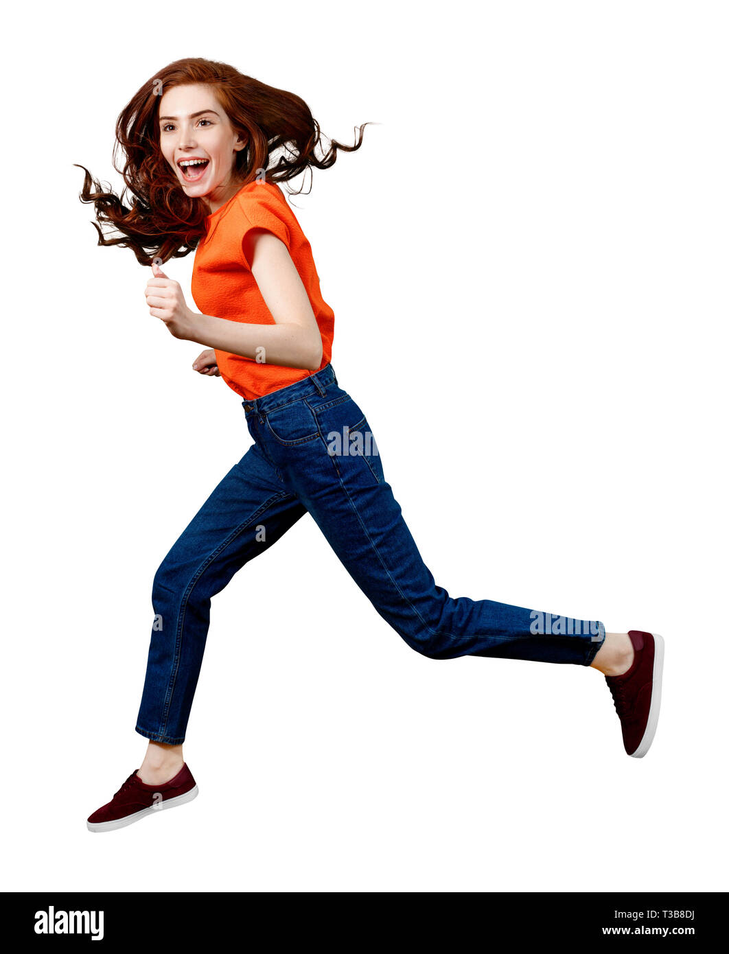 Full length happy ginger woman in shirt and jeans jumping. Stock Photo