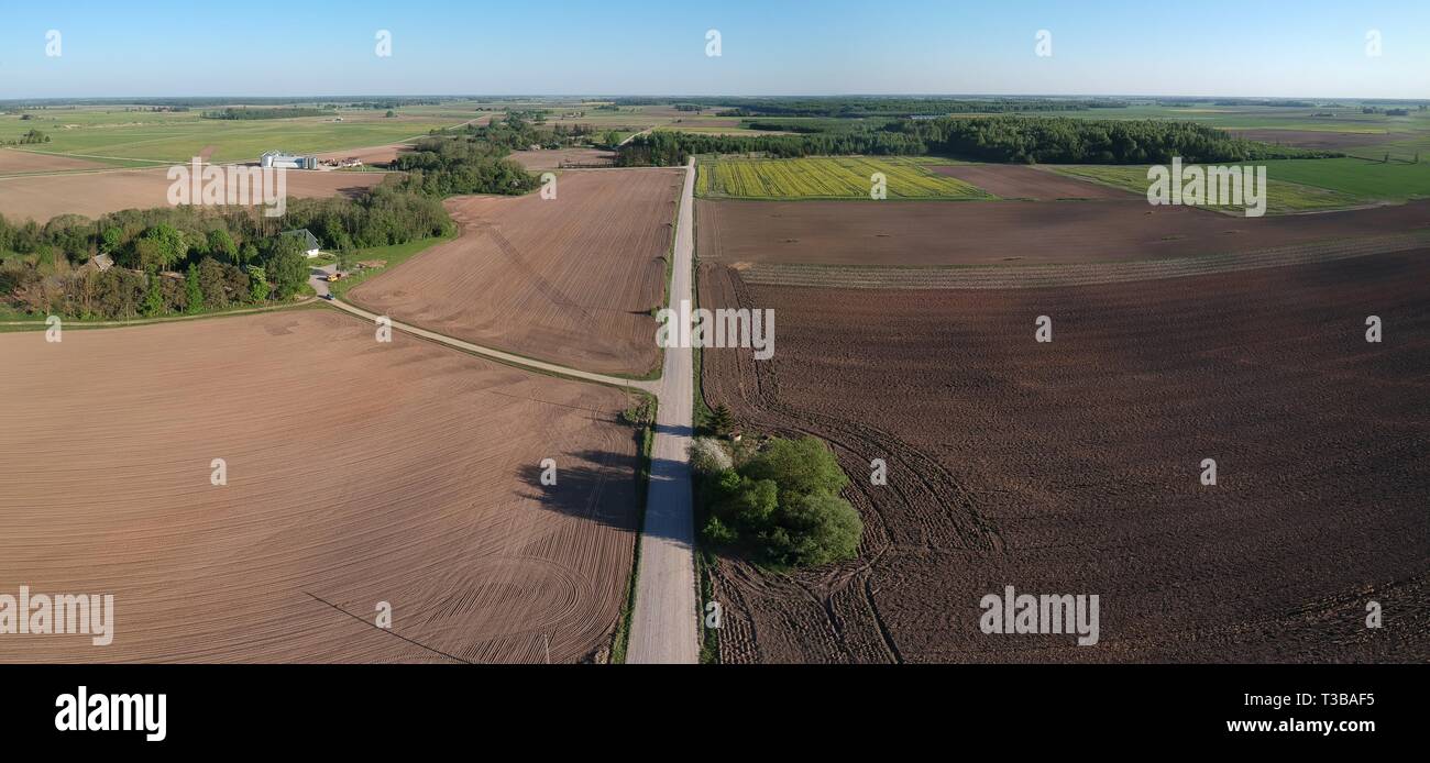 Cultivated farmland fields and white gravel road in spring, aerial view Stock Photo