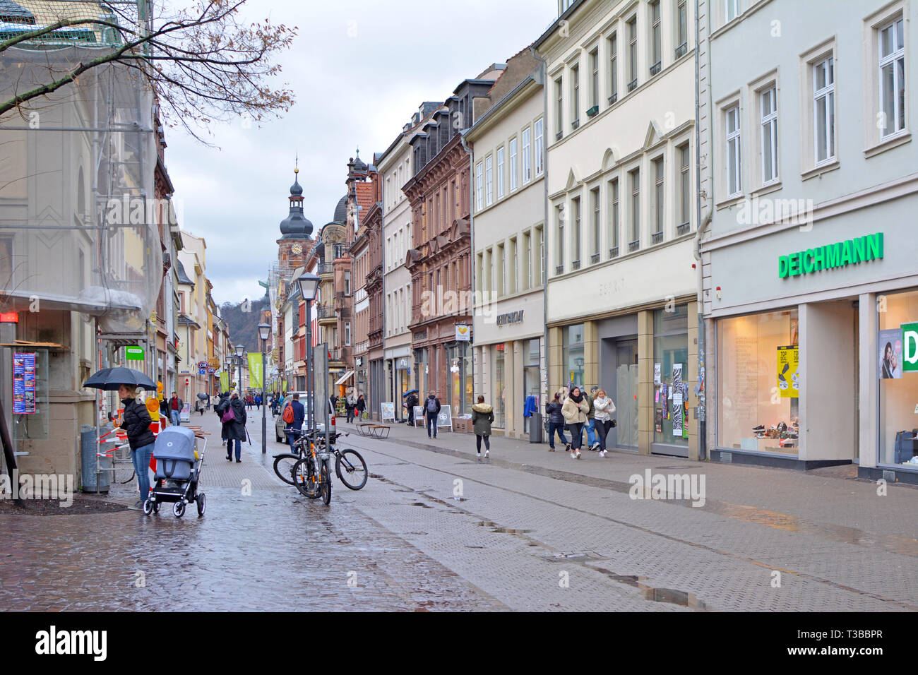 Main street with different stores in old buildings and few people in historical city center on a rainy day Stock Photo