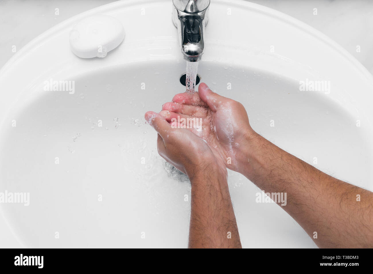Adult caucasian male washing hands with soap under the faucet with water Stock Photo