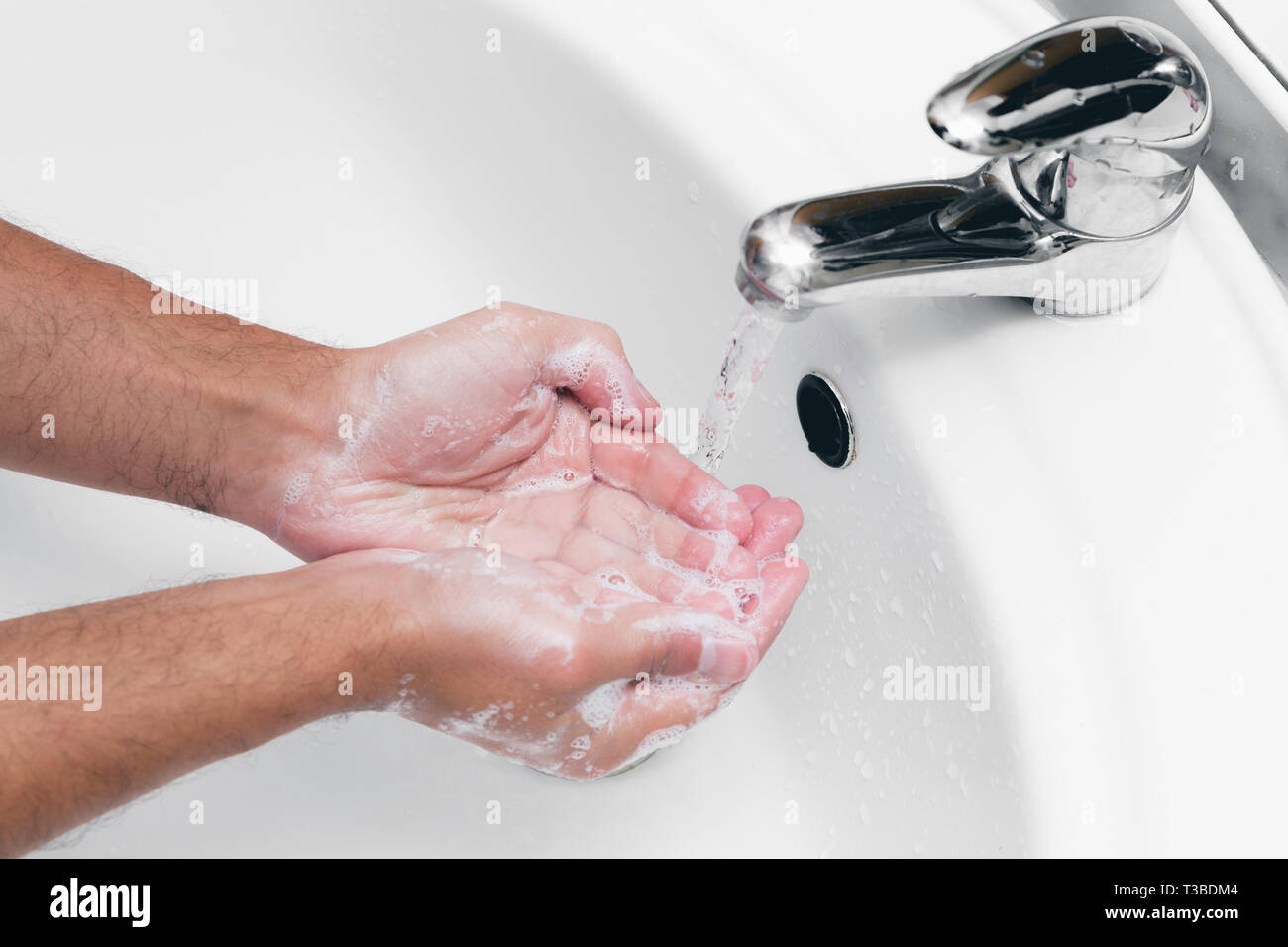 Adult caucasian male washing hands with soap under the faucet with water Stock Photo