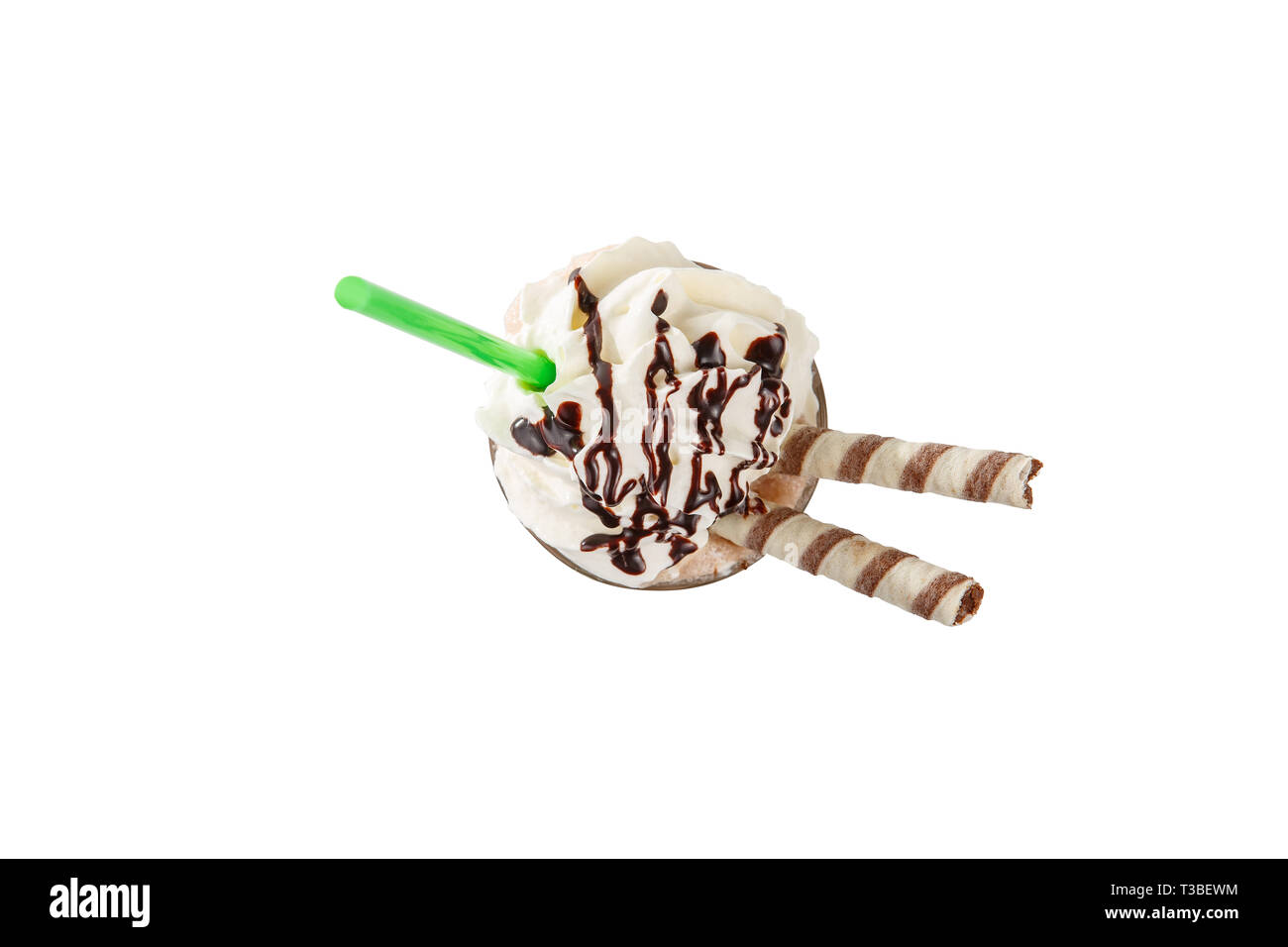 Milk cocktail with topping, chocolate syrup, wafer duct, green straw, isolated white background in a high glass and whipped cream, view from above Stock Photo