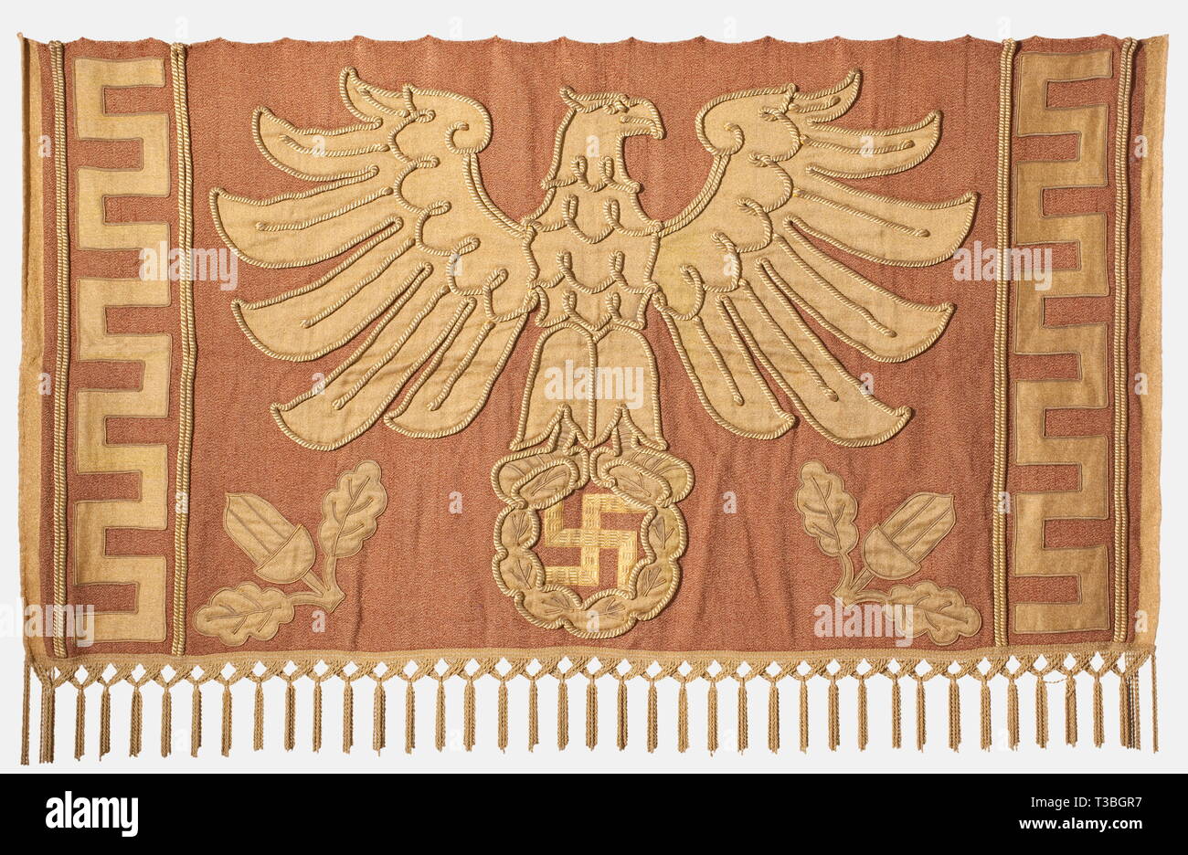 A decorative hanging for a parade float, in the procession '2000 Years of German Culture' in Munich 1938 Heavy cotton interwoven with gold and bearing an applied, gold coloured national eagle emblem outlined with gold cord on an oak leaf wreath. The swastika applied with gold braid, meander bordering on the sides. Forged iron suspension rings probably of later date. 130 x 215 cm. Probably a parade float banner of the 'Neue Zeit' ('New Era'). Cf. other decorative hangings of this kind in '2000 Jahre Deutsche Kultur', Bayerland Verlag, Munich 1938, p. 31 and in 'Festtage in M, Editorial-Use-Only Stock Photo
