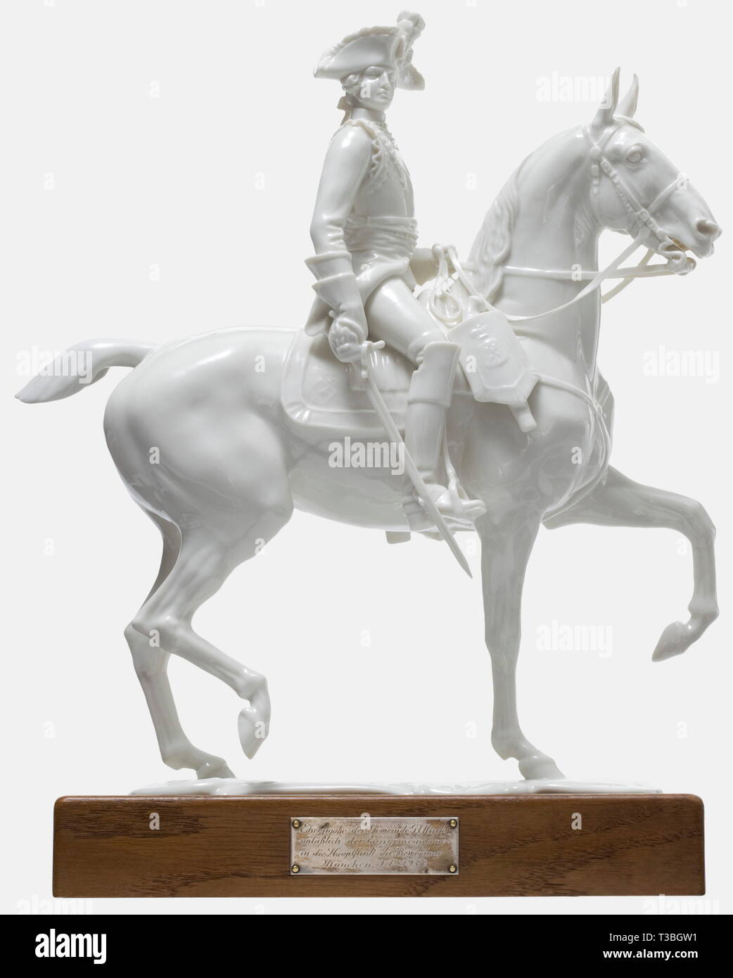 A Seydlitz-Cuirassier Officer with dedication of the Allach municipality 1938, Allach Porcelain Factory Design by Prof. Theodor Kärner. Model number '17'. White, glazed porcelain figure of a Prussian 18th century cuirassier. On the bottom the artist's signature, model number and manufacturer's pressmark 'SS Allach' in underglaze green and in an octagon. The tail and the reins of the horse restored. Height 31.5 cm. On a dedication base made from oak wood with customised sinking for the porcelain plinth of the figure on top and a pinned, silver dedication plaque 'Ehrengabe de, Editorial-Use-Only Stock Photo