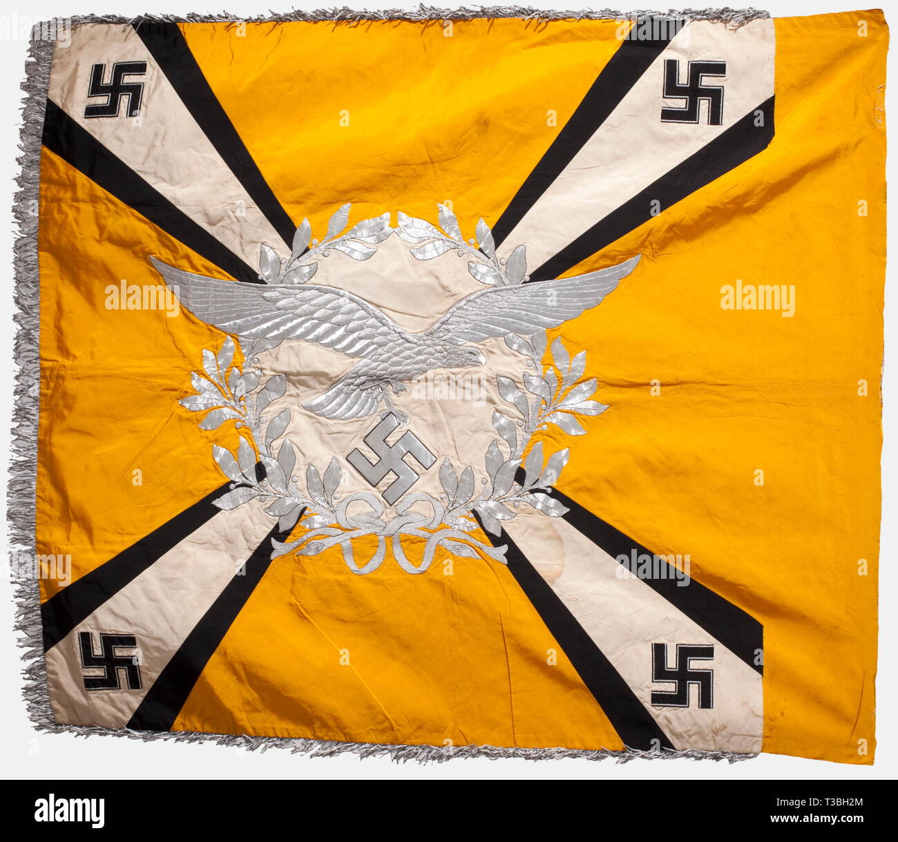 A banner for Luftwaffe flying units, or airborne units Made entirely of silk with silver fringe on three sides. Yellow with a white disc on both sides surrounded by a laurel wreath. A silver-embroidered Luftwaffe eagle with extended wings within the wreath on one side and an iron cross within it on the other. Four white diagonal rays with black edges widening towards the corners, which bear black silk swastikas with silver bordering. Bright colours. Marks of nails on the staff sleeve. Soiled. Traces of colour or mildew on the lower edge of the obverse side. Dimensions ca. 1, Editorial-Use-Only Stock Photo
