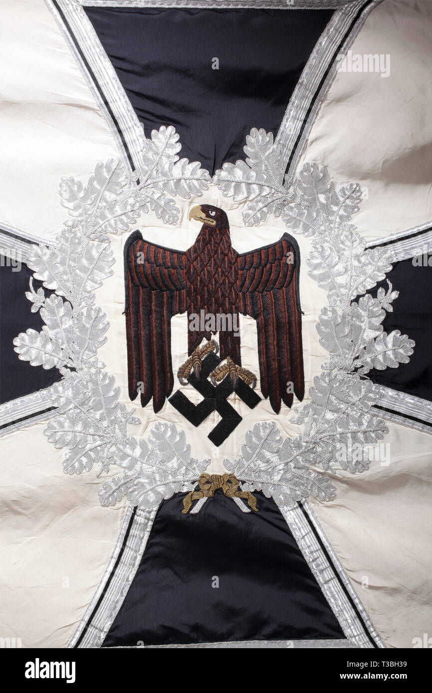 A standard for an infantry battalion, with the flag banderoler White silk with silver fringe on three sides. On both sides a hand-embroidered black army eagle with its feathers set off in brown. Beak and talons rendered in raised gold embroidery, on a field of cream-colored silk, surrounded by a silver-embroidered oak leaf wreath on an iron cross. An applied swastika in each of the corners. Dimensions ca. 125 x 125 cm. Banderole of aluminium fabric with a black/white/red interweave, complete with both clasps, displaying '16. März 1935', and '16. März 1936, No-Exclusive-Use | Editorial-Use-Only Stock Photo