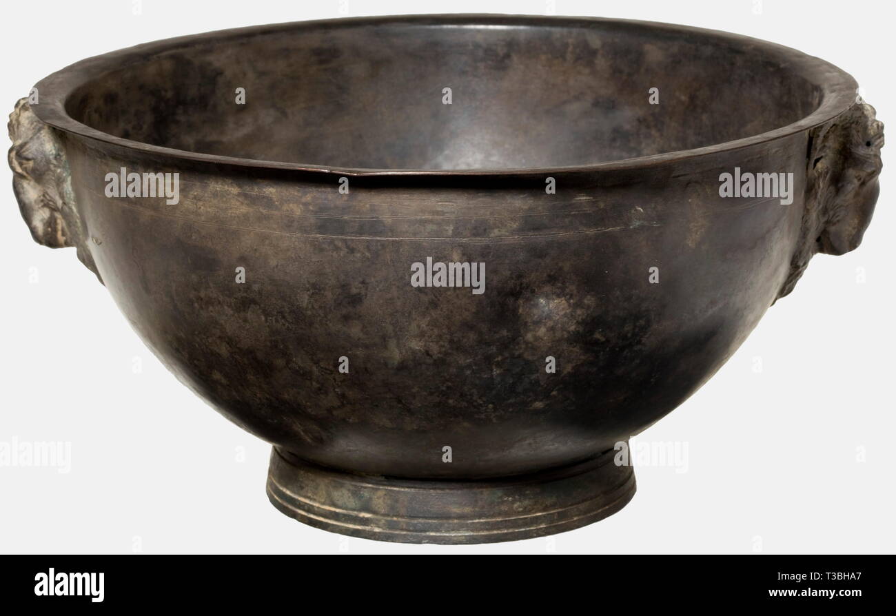 A Roman bronze bowl, 2nd/3rd century A.D. Bronze with even, dark green patina. Hemispherical body with a narrow, flanged rim. Slightly conical ring base, on the sides of the vessel two handles in the shape of goat heads. Cleaned archaeological find, slightly dented. Height 13, width 28 cm. historic, historical, ancient world, ancient world, ancient times, object, objects, stills, clipping, cut out, cut-out, cut-outs, Additional-Rights-Clearance-Info-Not-Available Stock Photo