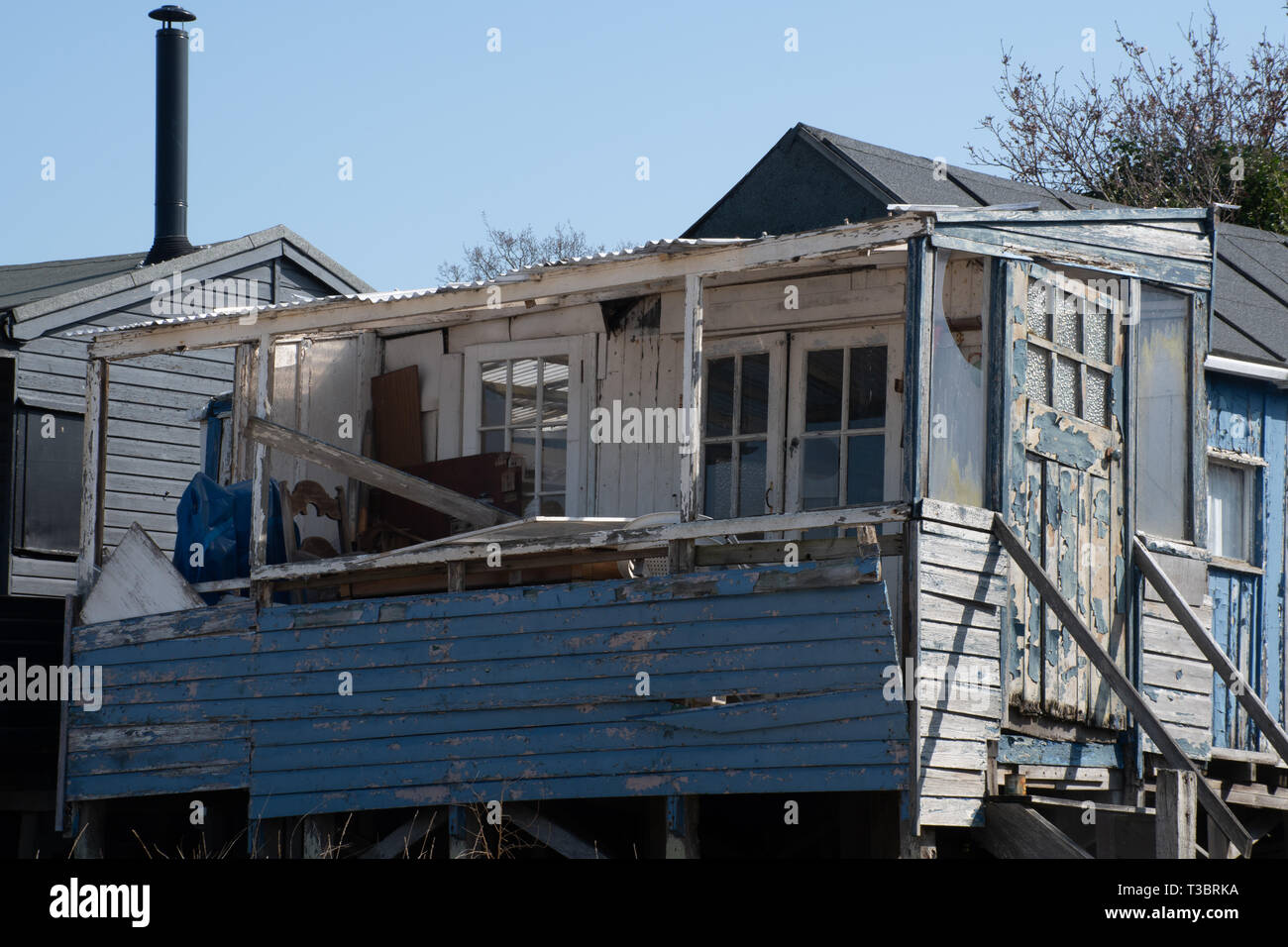 Run down blue large wooden shack by coast Stock Photo