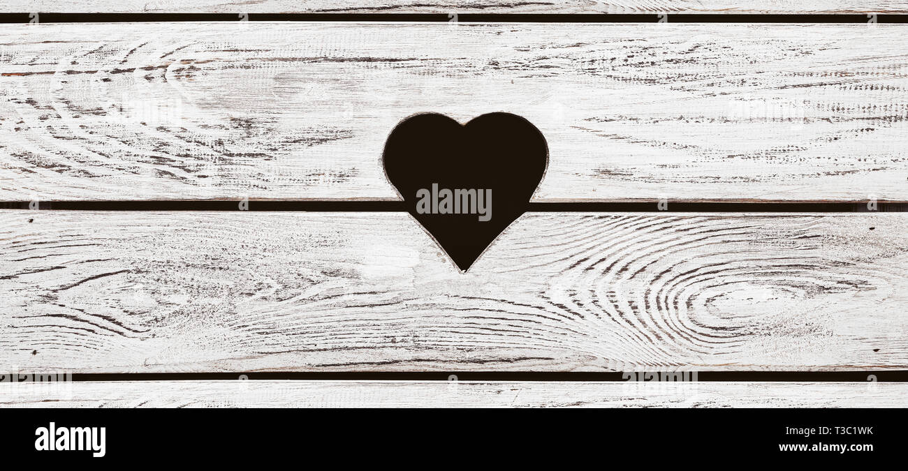 Heart shaped hole in the wooden background with copy space Stock Photo