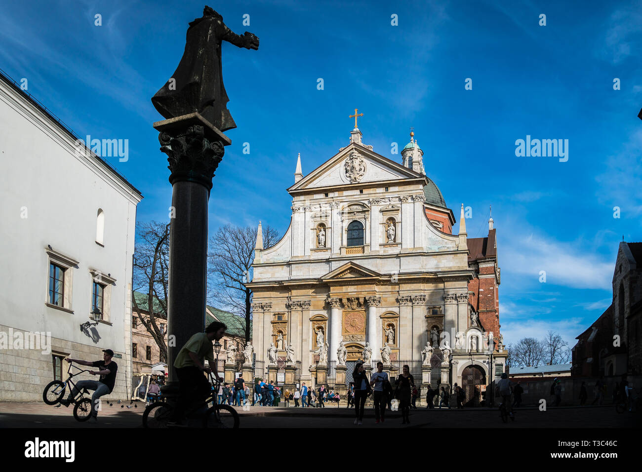 Krakow, Poland - March 22, 2019 - a boy on a cycle on a square in front of Saints Peter and Paul Church Stock Photo