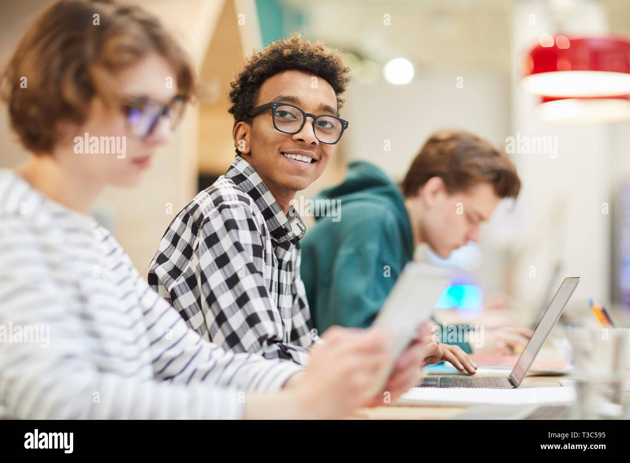 Cheerful smart black student using laptop Stock Photo