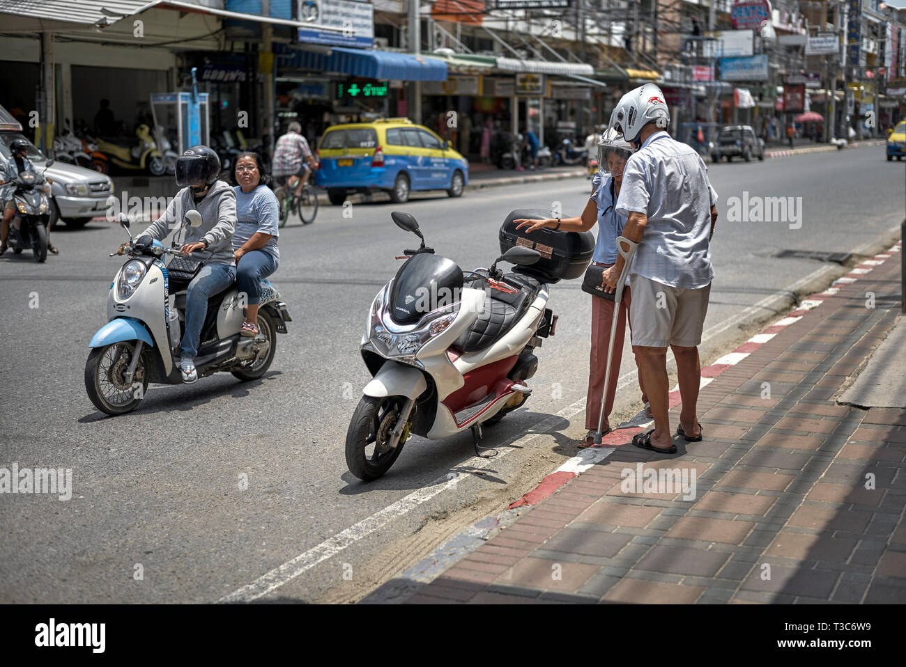 Man with crutches about to ride on a motorcycle. Thailand Southeast