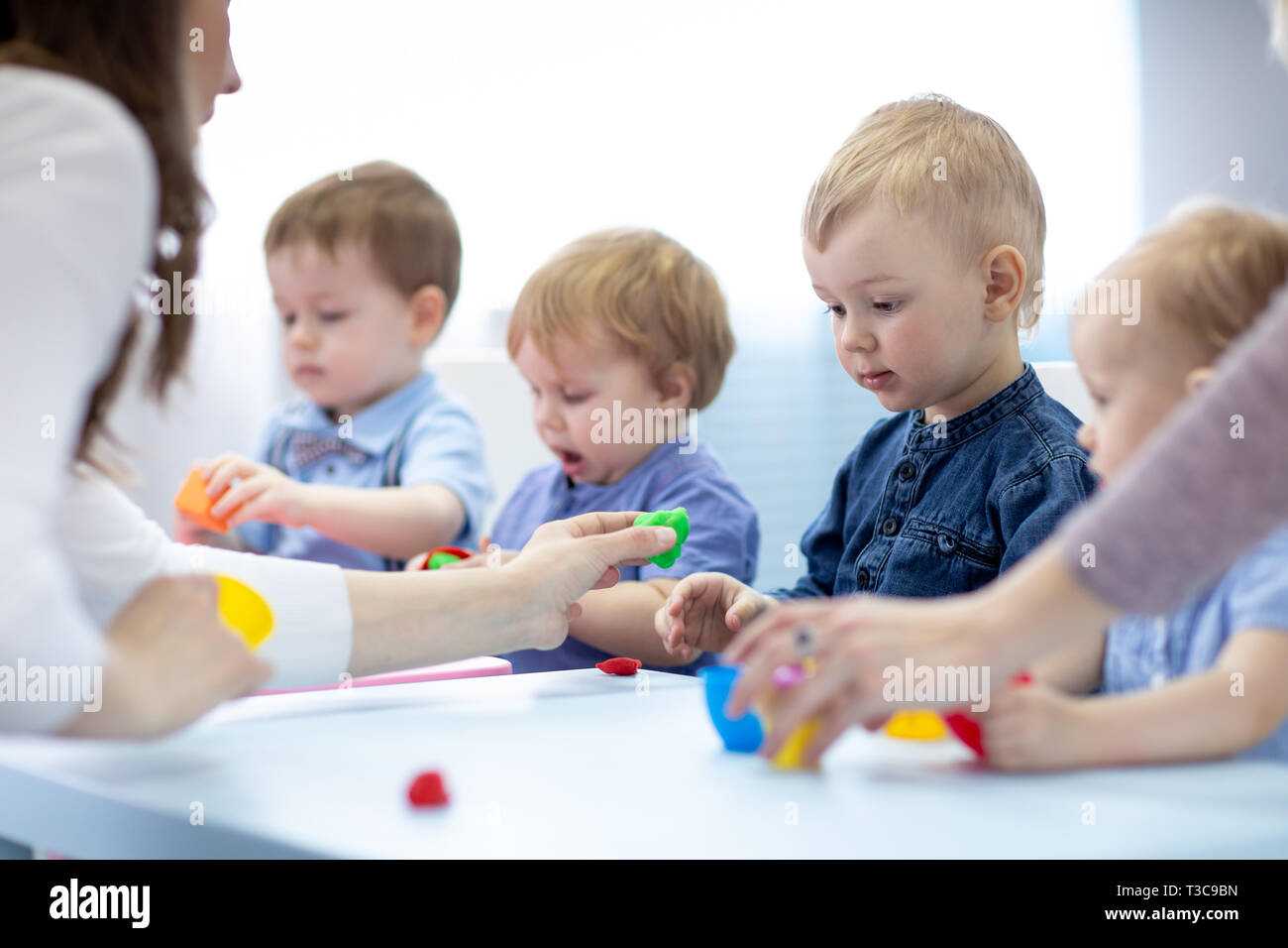 Children with teacher play colorful clay toy in kindergarten Stock ...