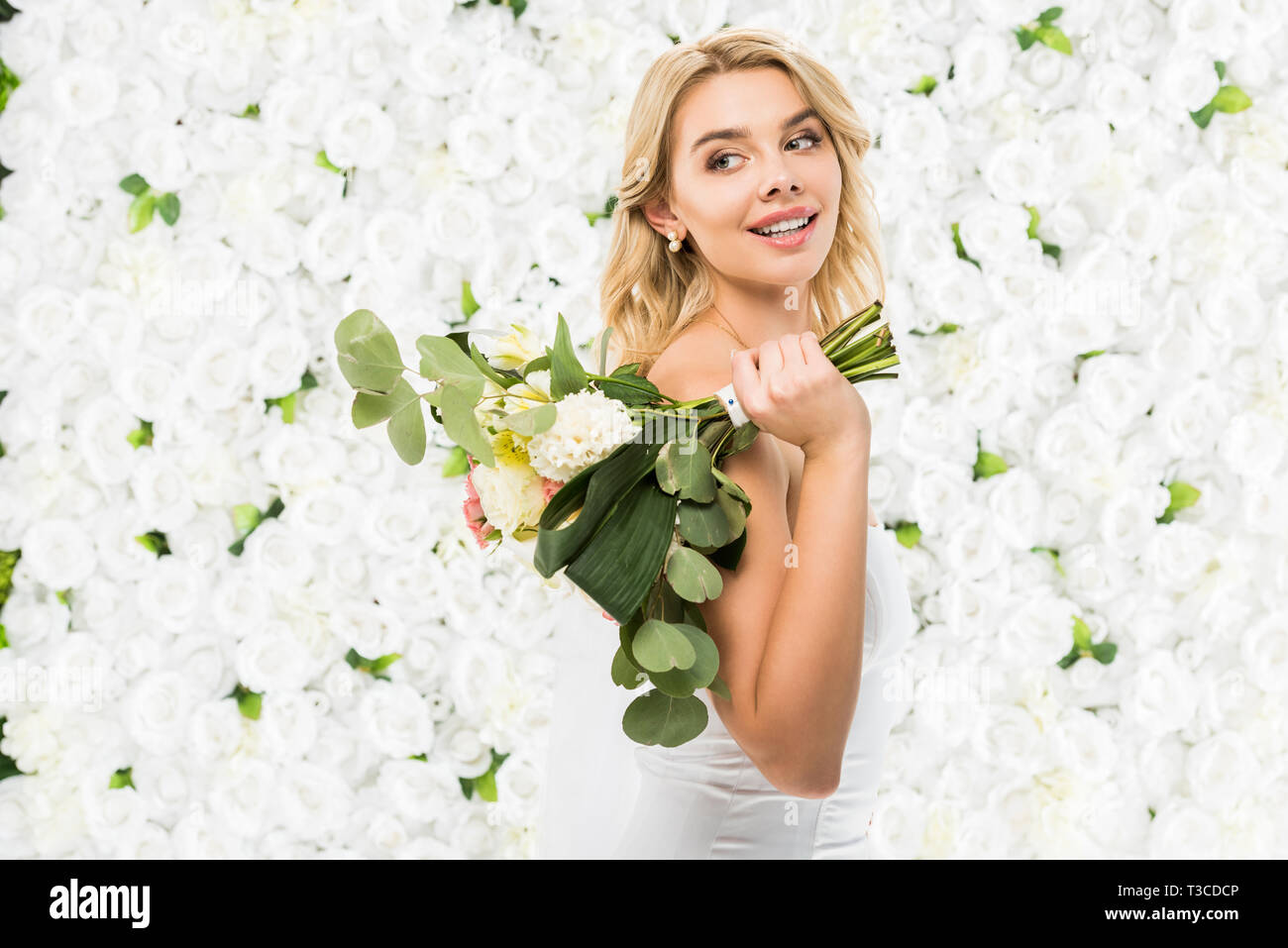 beautiful bride holding wedding bouquet on white floral background Stock Photo