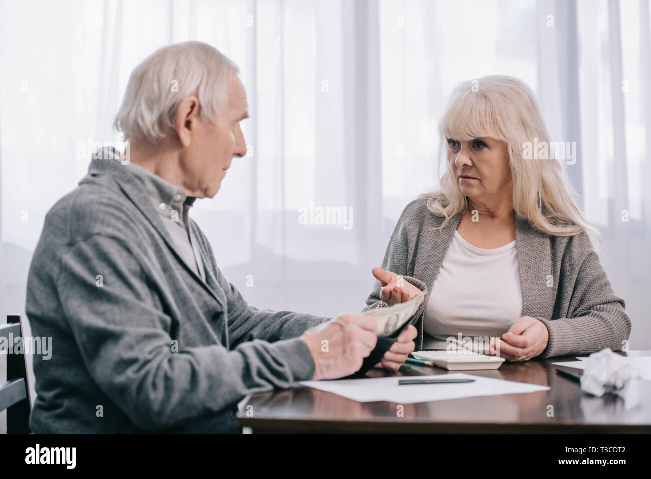 senior couple having discussion while sitting at table with paperwork Stock Photo